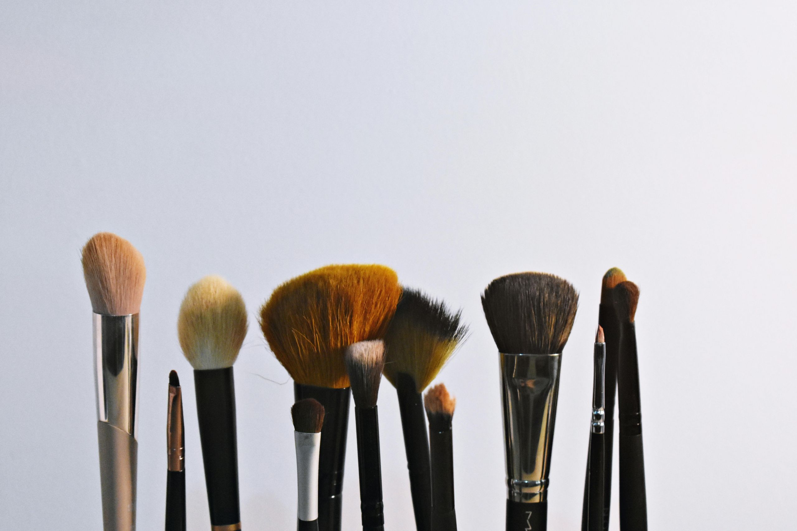 Various sized make-up brushes on a light background.